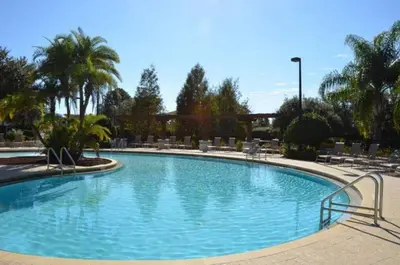 a large swimming pool with chairs and palm trees at 5372 Lovely home inside Disney area in Kissimmee