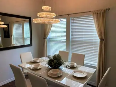 a dining room with a table and chairs and a mirror at 5372 Lovely home inside Disney area in Kissimmee