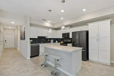 a large kitchen with white cabinets and a black refrigerator at 3120 BRAND NEW stunning apartment in Kissimmee