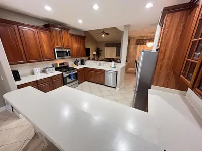 a kitchen with wooden cabinets and a white counter top at Mickeys Escape - Magical Lakeview 7BR - 4 Master Suites Pool & Hot Tub BBQ Home Theater and 2 Miles Disney! in Orlando