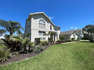a large house with a lawn in front of it at Mickeys Escape - Magical Lakeview 7BR - 4 Master Suites Pool & Hot Tub BBQ Home Theater and 2 Miles Disney! in Orlando