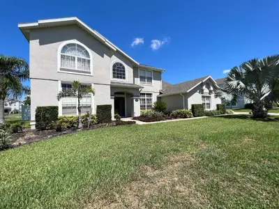 a large white house with a grass yard at Mickeys Escape - Magical Lakeview 7BR - 4 Master Suites Pool & Hot Tub BBQ Home Theater and 2 Miles Disney! in Orlando