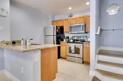 a kitchen with wooden cabinets and stainless steel appliances at 12 Mi to Disney Family Home with Resort Amenities! in Kissimmee