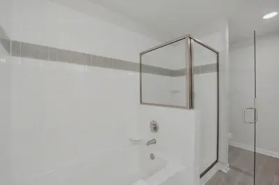 a white bathroom with a shower and a mirror at Newly Renovated Condo wFREE Resort Access in Orlando