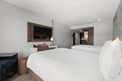 a bedroom with two white beds and a flat screen tv at Cambria Hotel Orlando near Universal Theme Parks in Orlando