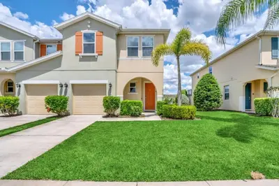 a house with a palm tree in front of it at 4 Bed townhome with Private Pool Near Disney! townhouse in Kissimmee