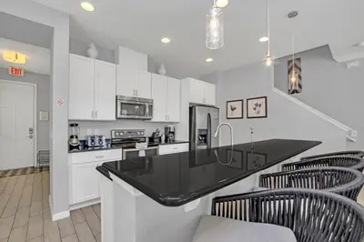 a kitchen with white cabinets and a black counter top at 4 Bed townhome with Private Pool Near Disney! townhouse in Kissimmee