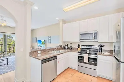 a kitchen with white cabinets and a stove top oven at Relaxing 3BR Near Disney - Pool in Orlando