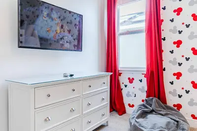 a bedroom with a dresser and a window with red curtains at Encore Resort 5 Bedroom Home with Pool 2201 in Orlando