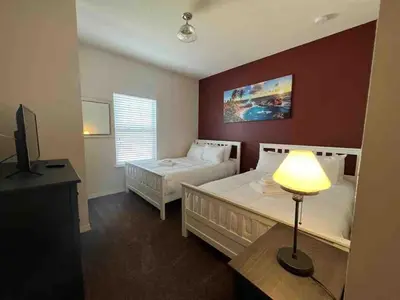 a bedroom with two beds and a lamp and a television at Super Comfy and Spacious 3 Bedroom 15-20 minutes from Disney, with major shopping 4 minutes away in Kissimmee