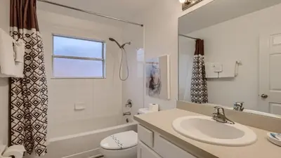 a bathroom with a sink and a toilet and a window at Magical 7BR Resort Pool Home Near Disney & Orlando Attractions in Kissimmee