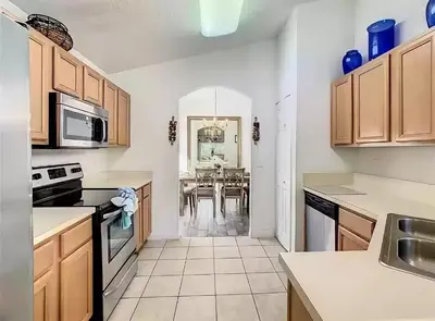 a kitchen with wooden cabinets and a dining room at Family Oasis 5BR Villa with South Facing Pool and Games Room Near Disney in Kissimmee