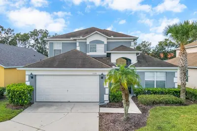 a house with a garage and palm trees at Family Oasis 5BR Villa with South Facing Pool and Games Room Near Disney in Kissimmee