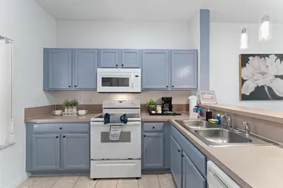 a kitchen with blue cabinets and a stove and a sink at JC DISNEY House in Kissimmee