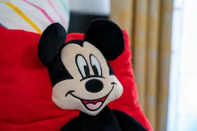 a stuffed mickey mouse is sitting on a red pillow at JC DISNEY House in Kissimmee