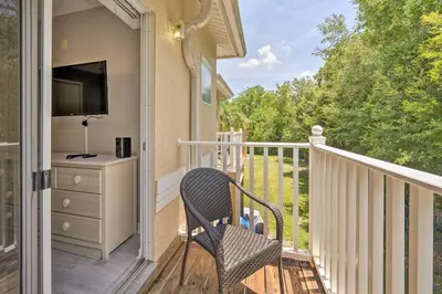 a porch with a chair and a television on a balcony at 9 Mi to Disney Resort Getaway with Private Patio! in Kissimmee