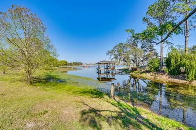 a house on the river with a dock on the water at Lakefront Retreat with Kayaks and Fire Pit in Clermont in Clermont