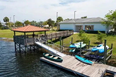 a dock with boats on the water next to a house at Gorgeous 4Bd w/ Pool Close to Disney @ Storey Lake 4289 in Kissimmee