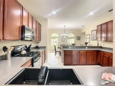 a large kitchen with wooden cabinets and a sink at Fantastic 7 Bed 6 Bath in Prestigious Gated Comm, villa in Orlando