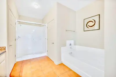 a white bathroom with a tub and a shower at 3BR Condo with Pool - Near Disney in Orlando