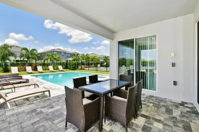 a patio with a table and chairs and a swimming pool at Modern Home Near Disney With Private Pool And Waterpark & Resort Access At Encore Resorts Reunion - 393Sf in Kissimmee