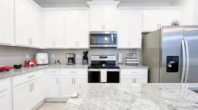 a kitchen with white cabinets and a stainless steel refrigerator at NEW! Solara Pool Home 6 Miles to Disney in Kissimmee
