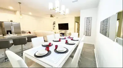 a white dining room with a white table and white chairs at NEW! Solara Pool Home 6 Miles to Disney in Kissimmee
