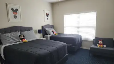 a bedroom with two beds and a chair and a window at My Home in Orlando in Kissimmee