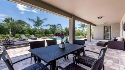 a patio with a table and chairs and a pool at Elegant Fun Vacation Home at Encore Resort 7529 in Orlando