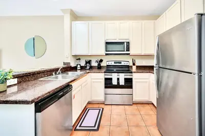 a kitchen with white cabinets and a stainless steel refrigerator at 3BR Condo with Pool Close to Disney in Orlando