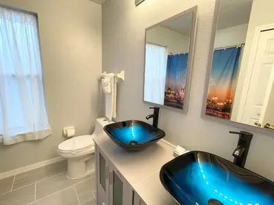 a bathroom with a blue sink and a toilet at Fully Renovated, Quiet, Spacious Disney Themed Pool Home with Office in Kissimmee