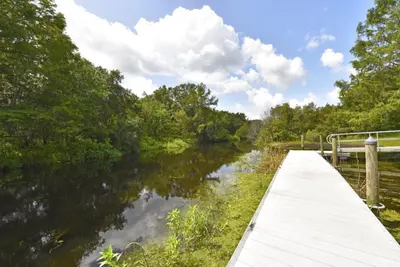 a wooden walkway over a river with trees at Lakeside 4-Bed Pool Home at Villa Sol home in Kissimmee
