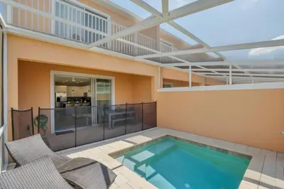 a swimming pool on a patio with two chairs at 1511RETREAT townhouse in Orlando