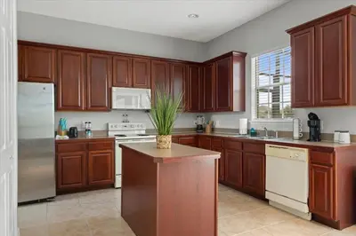 a kitchen with wooden cabinets and a white appliance at LONG STAYS! Lakefront - Gated Pool Home in Orlando