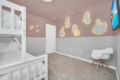 a bedroom with a bunk bed and a white chair at 8 Bedroom 6 Bathroom Resort Home villa in Kissimmee