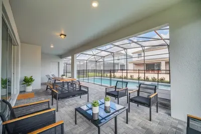 a patio with tables and chairs and a swimming pool at 8 Bedroom 6 Bathroom Resort Home villa in Kissimmee