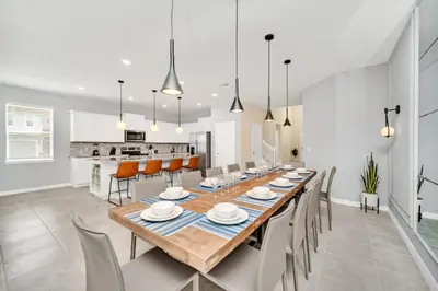 a dining room and kitchen with a long table and chairs at 8 Bedroom 6 Bathroom Resort Home villa in Kissimmee