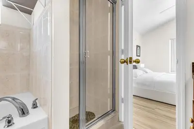 a bathroom with a shower and a sink and a bed at Disney Area 4BR Home with Heated Private Pool in Kissimmee