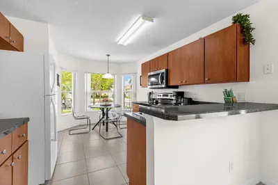 a kitchen with wooden cabinets and a table in a room at Disney Area 4BR Home with Heated Private Pool in Kissimmee