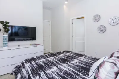 a white bedroom with a bed and a tv at Magical Retreat: Luxurious Home near Disney World in Kissimmee