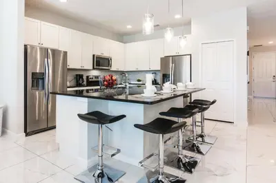 a kitchen with a island with bar stools at Magical Retreat: Luxurious Home near Disney World in Kissimmee