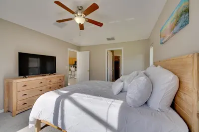 a bedroom with a bed with a ceiling fan and a television at Kissimmee Getaway with Pool about 7 Mi to Disney! in Kissimmee