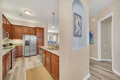 a kitchen with wooden cabinets and stainless steel appliances at Lakeview Condo Directly Next To Pool Near WDW in Orlando