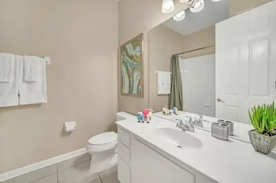 a white bathroom with a sink and a toilet at Lakeview Condo Directly Next To Pool Near WDW in Orlando