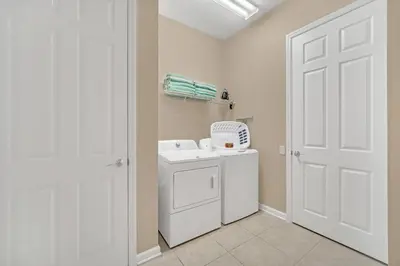 a laundry room with a washing machine and a white door at Lakeview Condo Directly Next To Pool Near WDW in Orlando