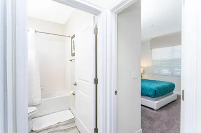 a bathroom with a tub and a toilet and a bed at Blue Moon House in Kissimmee