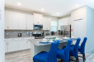 a kitchen with white cabinets and a table with blue chairs at Blue Moon House in Kissimmee