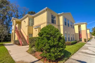a large yellow house with a tree in front of it at Club Cortile 3 Bedroom Condo Resort Pool 8 Miles to Disney in Kissimmee