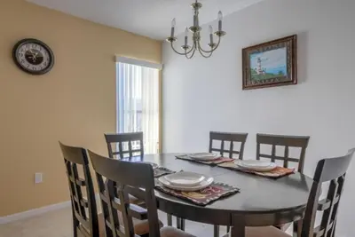 a dining room with a table with chairs and a clock at Club Cortile 3 Bedroom Condo Resort Pool 8 Miles to Disney in Kissimmee