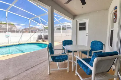 a patio with a table and chairs next to a swimming pool at Clear Creek 3 Bedroom Home Private Pool 15 Min to Disney in Orlando